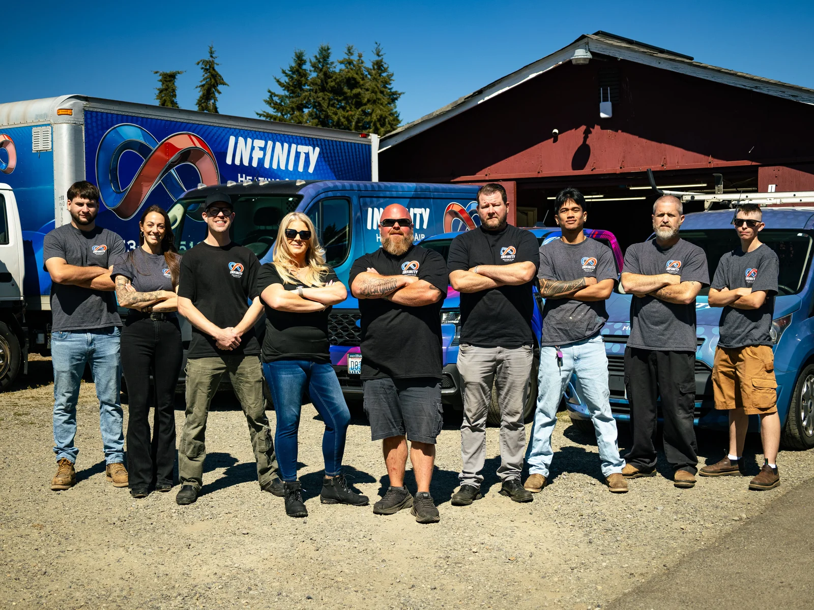 The Infinity Heating & Air crew standing together in front of their branded trucks in Graham, WA